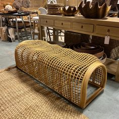 a wicker bench sitting on top of a wooden floor next to baskets and bowls