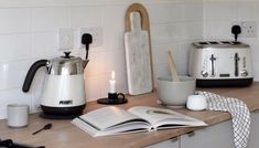 the kitchen counter is clean and ready to be used as a coffee pot, toaster, tea kettle, mugs and utensils