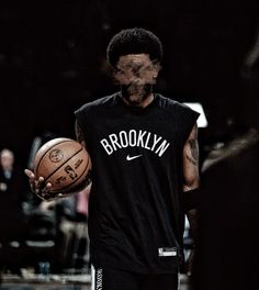 a man holding a basketball while wearing a black shirt with brooklyn written on the front