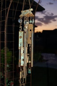 an old wind chime hanging from a metal fence at night with the sun setting in the background