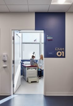 an exam room with two people sitting at a desk in front of the door and on the wall