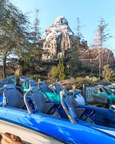 there are many blue and white boats lined up in front of a mountain with snow on it