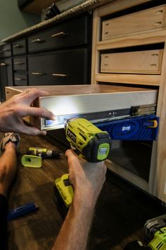 a man is working on a cabinet door with tools in his hand and some screwdrivers