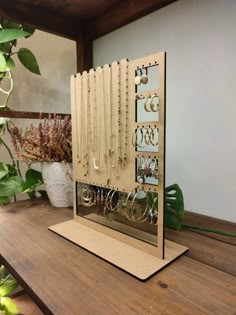 a wooden display with many pairs of earrings on it and a plant in the background