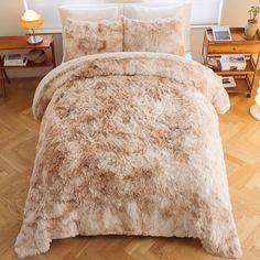 a bed covered in a fluffy brown fur comforter next to a night stand with a lamp on it