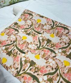 an image of a bed with white sheets and floral designs on the comforter cover