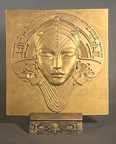 a golden plaque with a woman's face in the center and an intricate design on it