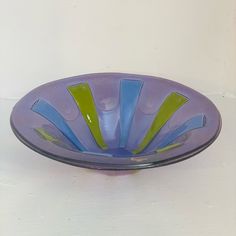 a purple glass bowl sitting on top of a table