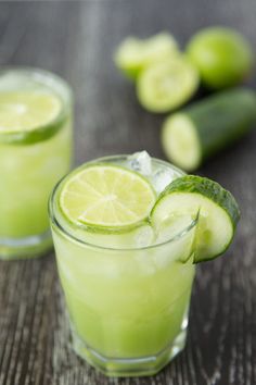 two glasses filled with cucumber and limeade on top of a wooden table