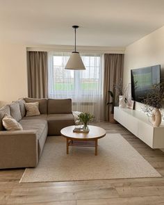 a living room filled with furniture and a flat screen tv on top of a wooden table