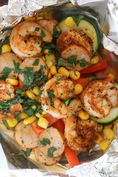 shrimp, corn and zucchini on tin foil with garnish in the middle