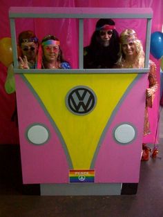 some people are standing in a pink and yellow vw camper van with balloons