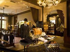 a man's suit and hat is on display in a store with mannequins