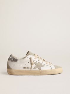 A timeless icon yet one that’s constantly evolving. At Golden, we love taking our classics and reworking them all the time, always from a new angle. These Super-Star sneakers with a white leather upper feature an ice-gray suede star and a silver glitter heel tab. The ice-gray suede insert and tongue and cream laces add the finishing touch. Golden Goose Slippers, Golden Goose Women, Silver Glitter Heels, Golden Family, Gold Glitter Stars, Constantly Evolving, Lace Jewelry, Glitter Heels, Lace Socks