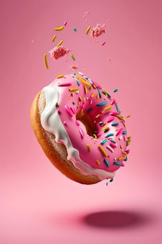 a donut with pink icing and sprinkles is in the air