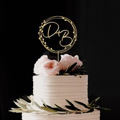 a three tiered cake with white frosting and gold monogramming on top