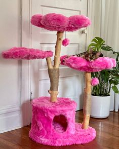 a cat tree that has pink fur on it and is next to a potted plant