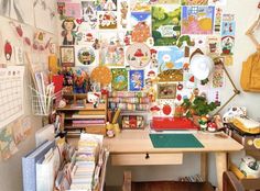 a cluttered desk with lots of pictures on the wall and bookshelves in front of it