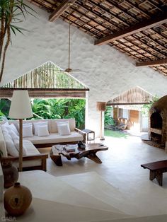 a living room with white couches and tables in front of an open fire place