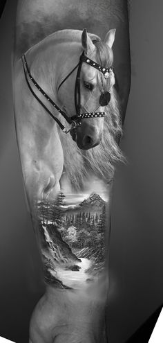 a man's arm with a horse and mountain scene on it