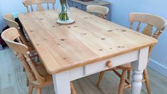 a wooden table with chairs around it and a vase filled with flowers on the top