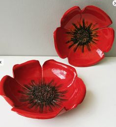 two red flower shaped bowls sitting on top of a white counter next to each other