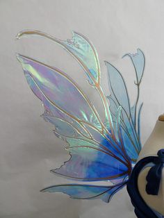 a vase with a blue and white butterfly decoration on it's side, next to a glass sculpture