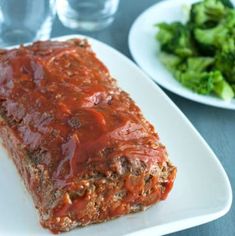 meatloaf on a white plate with broccoli and water glasses in the background