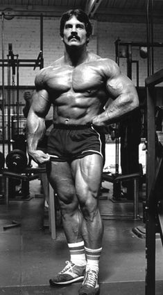 a man standing in the middle of a gym with his hands on his hips and looking at the camera