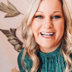 a woman with blonde hair and blue eyes smiles at the camera while wearing a green sweater