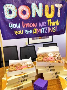 two boxes filled with donuts sitting on top of a table next to a sign