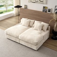 a white couch sitting on top of a hard wood floor next to a wall mounted painting