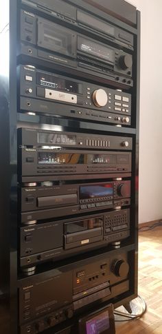 a large stack of electronics sitting on top of a hard wood floor next to a wall