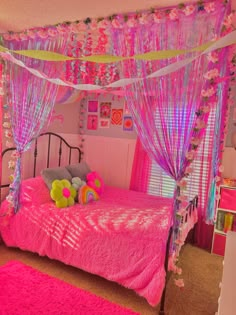 a bedroom decorated in pink, purple and yellow with flowers on the bed canopy over it