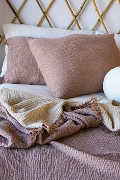 a bed with pillows and blankets on top of it next to a white ball in the middle