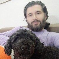 a man sitting on top of a couch holding a black dog next to an orange ball