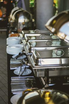 the buffet table is full of silver dishes