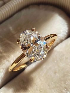 a diamond ring sitting on top of a white furnishing bag with a gold band