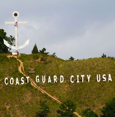 there is a sign that says coast guard city usa on top of a hill with an anchor