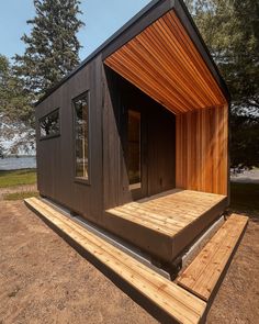 the tiny house is built on top of a wooden platform and has an open door