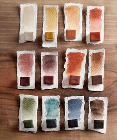 several different shades of paint sitting on top of a wooden table next to each other