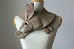 a white mannequin with a gray rabbit scarf on it