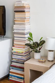 a stack of books sitting on top of a table next to a tv and lamp