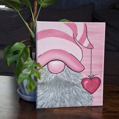 a potted plant sitting on top of a wooden table next to a pink and white painting