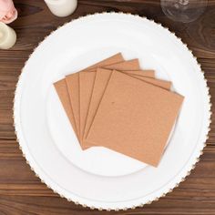 four pieces of brown paper sitting on top of a white plate next to a candle