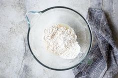 a glass bowl filled with flour sitting on top of a table next to a napkin