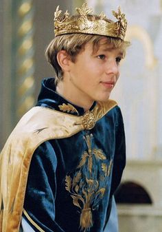 a young boy wearing a blue and gold outfit with a crown on his head,