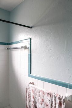 a bathroom with blue and white tile on the walls, shower curtain in the foreground