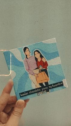 someone holding up a card with an image of two women on it