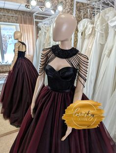 a mannequin wearing a black and burgundy dress in front of dresses on display